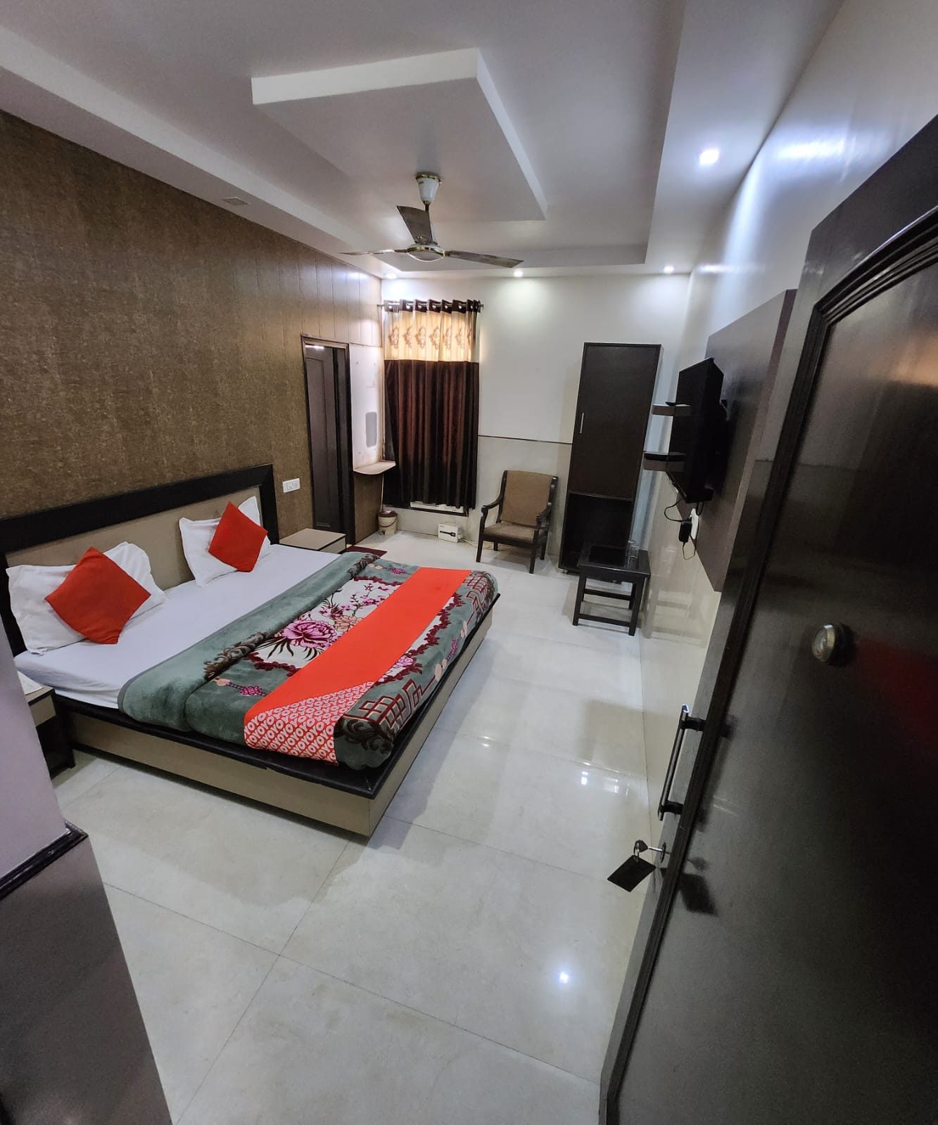 Deluxe Room at Hotel Uttam Heritage — double bed against a textured stone-effect wall