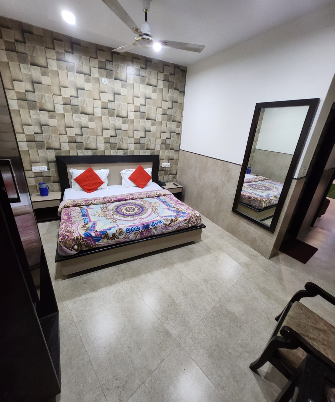 A Deluxe Room with a mosaic stone feature wall and a full-length mirror