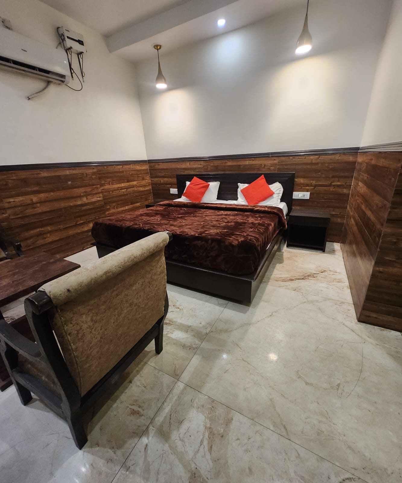 An Executive Room at Hotel Uttam Heritage — walnut-panelled walls, a double bed and a carved sofa on a marble floor